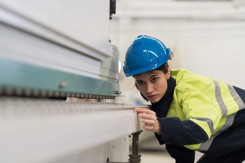 female worker examining conveyor belt for safety