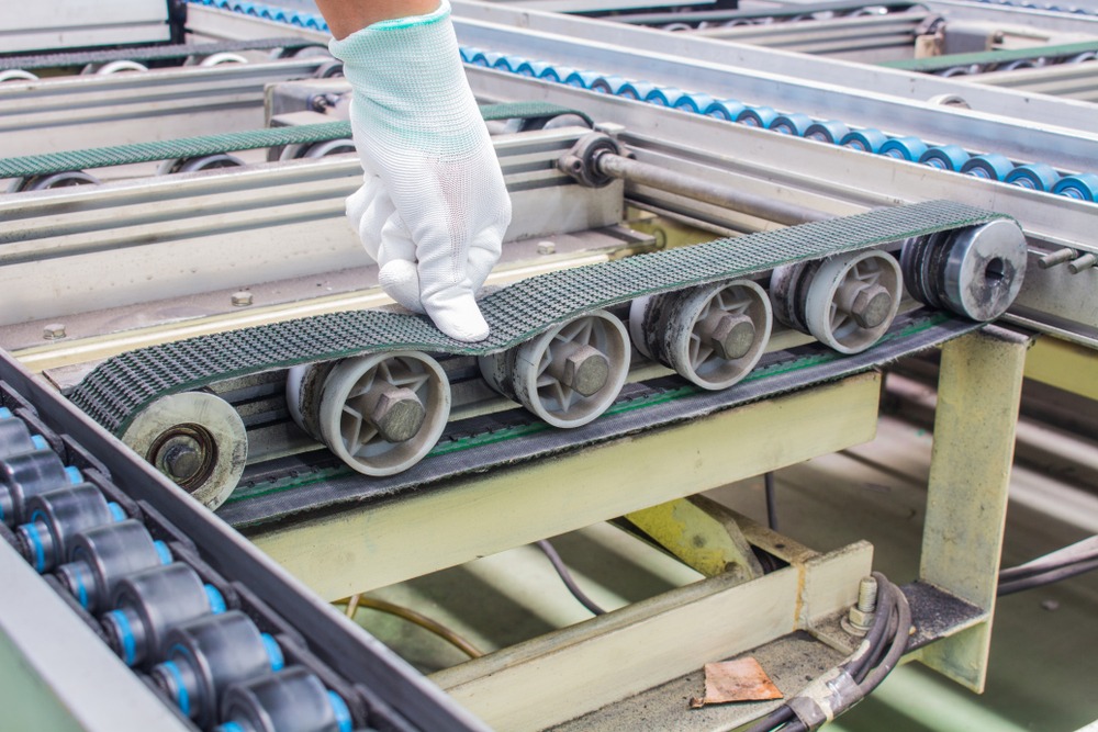 worker examining conveyor belt for proper tension