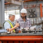 2 manufacturing employees discuss design solutions