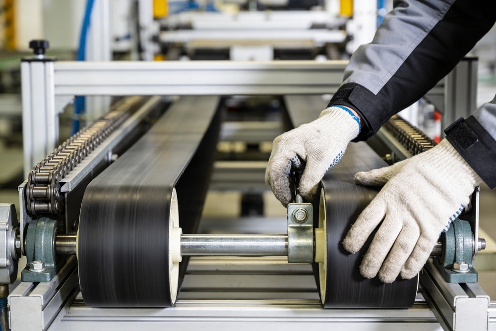 Closeup of technician's hands as they adjust conveyor belt tension