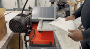 Employee hand-stitches a belt with industrial equipment